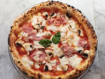 Neapolitan pizza with mozzarella, mushrooms, prosciutto, and fresh basil.