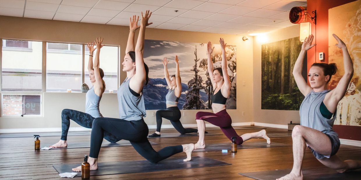 Group yoga session with participants stretching indoors in a serene studio.