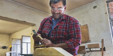 Man in plaid shirt working on woodworking project in a workshop.