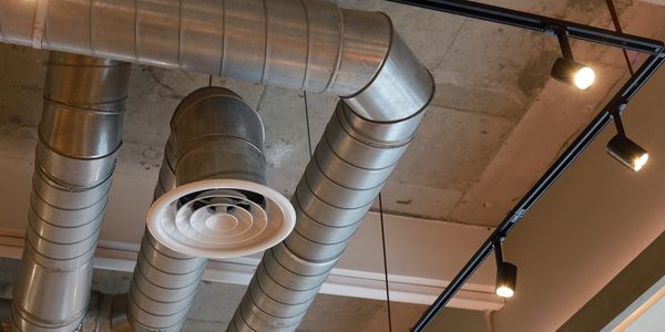 Exposed industrial air ducts and ceiling lights in a modern building.
