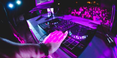 DJ performing live with a crowd in the background.