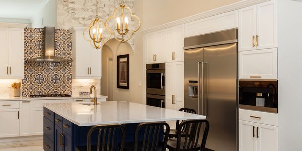 Modern kitchen with white cabinets, a navy island, and gold fixtures.