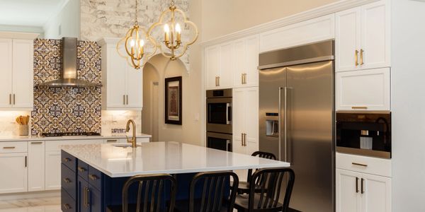 Modern kitchen with white cabinets, a navy island, and gold fixtures.