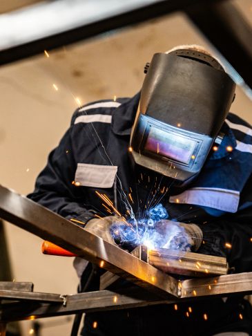 Welder working with sparks and protective gear.