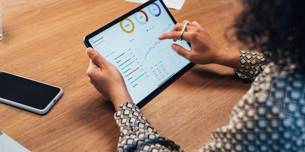 Pessoa usando tablet para analisar gráficos e dados.