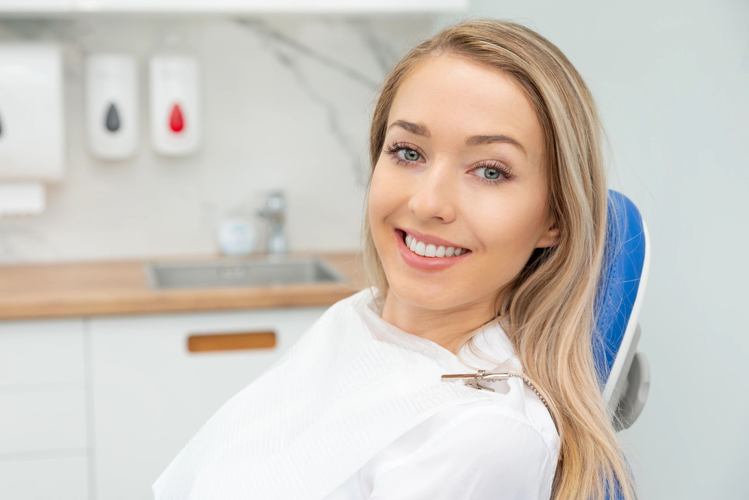 Smiling young woman sitting in a dental chair with a bib.