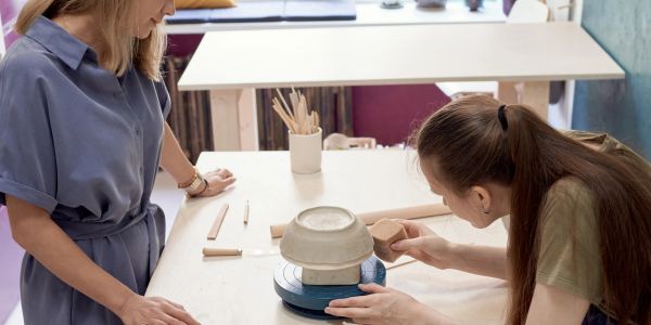 Two women working on pottery at a table.
