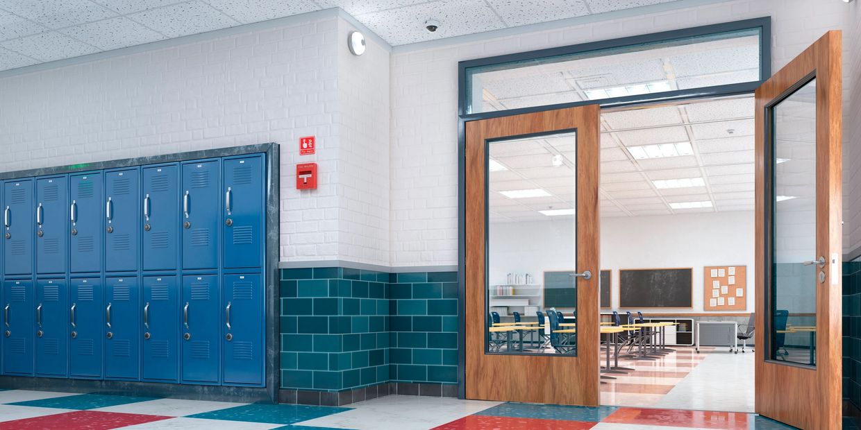 Empty school hallway with blue lockers and an open classroom door.