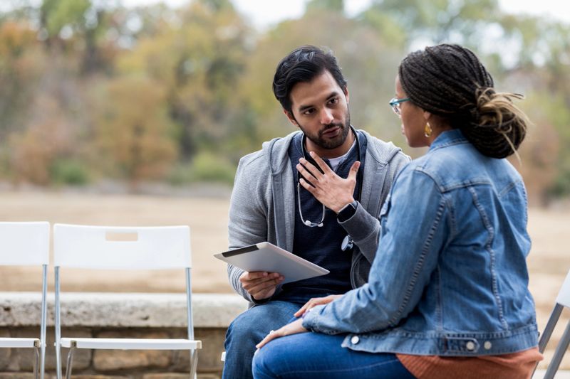 As the patient waits to see a doctor at the free clinic, the volunteer male nurse gestures while asking her questions.