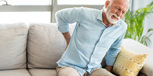 Older adult man with low back pain sitting on a couch
