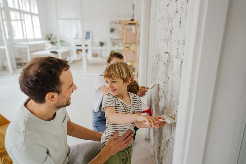Photo of a young family painting walls in the living room of their apartment.