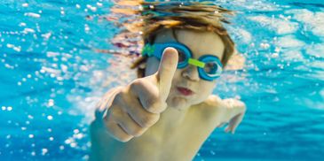 A child thumbs up inside the river