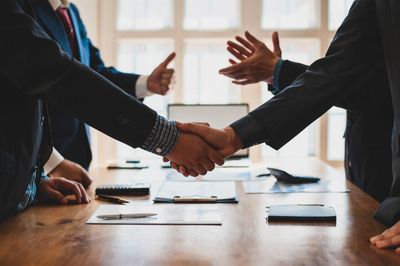 Two business professionals shaking hands over a meeting table.