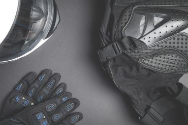 Motorcycle helmet, gloves, and jacket arranged on a dark surface.