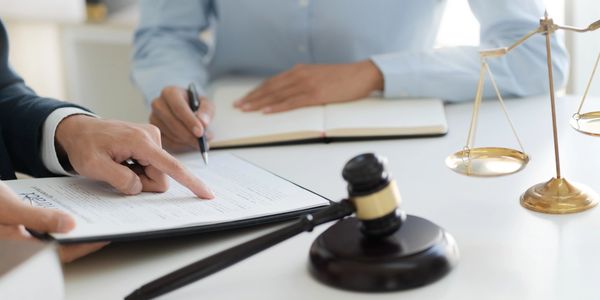 Two people reviewing a legal document with a gavel and scales of justice on the table.