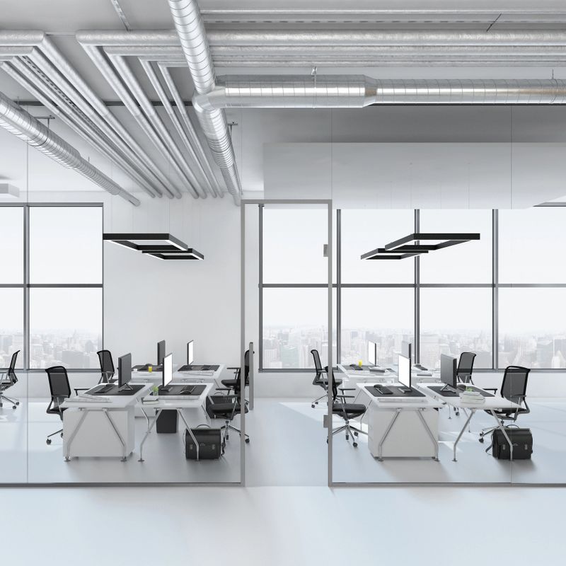 Modern office interior, many work stations with desktop computer and large LCD screen. White floor and minimalist materials. no people, large windows with sunlight. open plan. template copy space render