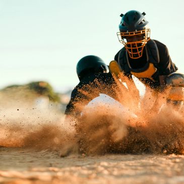 Two baseball players collide, kicking up a cloud of dirt on the field.
