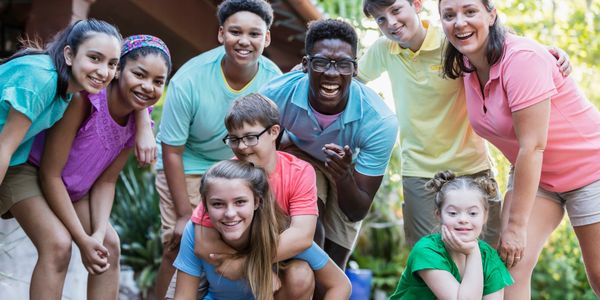 A diverse group of happy young people posing together outdoors.