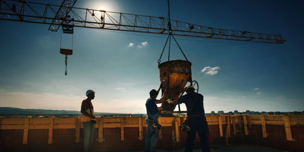 Construction workers operating a crane at dusk.