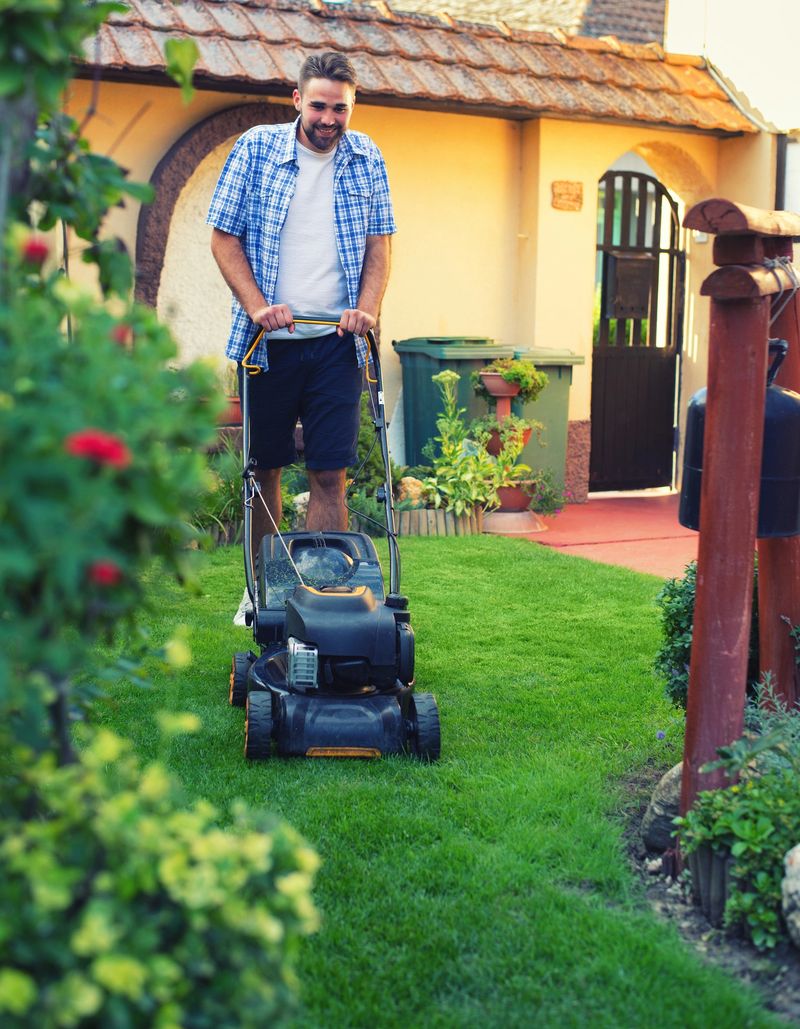 Man using a lawn mower in his back yard in summer.