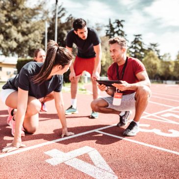Coach giving instructions to athletes on a running track.