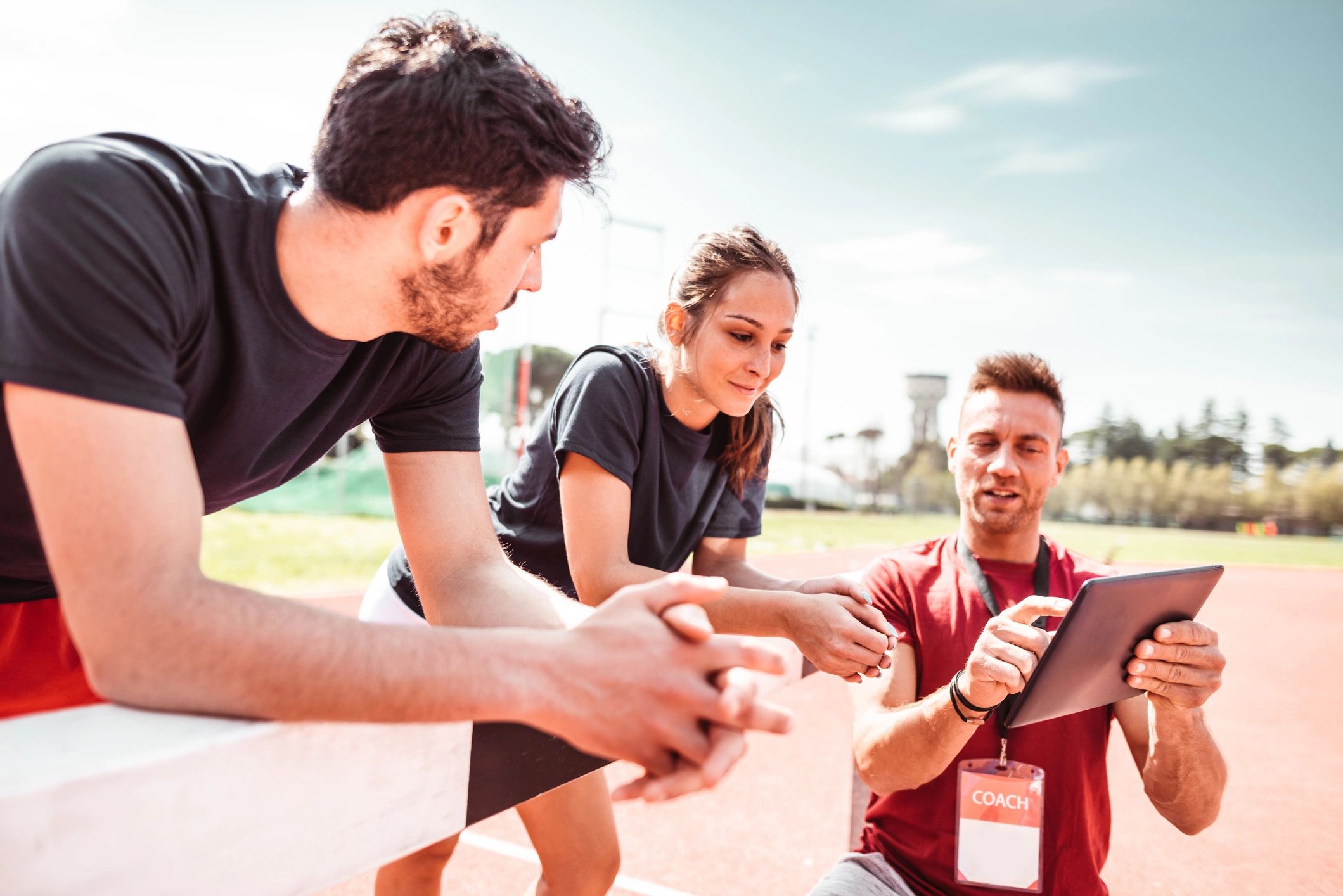 Coach discussing strategies with athletes outdoors.