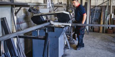 A man operating a metal cutting machine in a workshop.