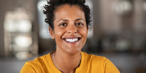 Smiling woman in a yellow shirt looking at the camera.
