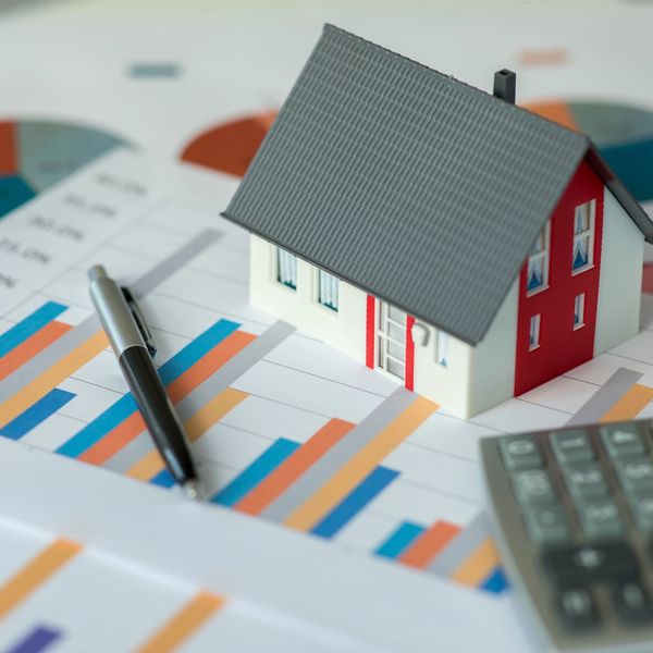 A model house on financial charts with a pen and calculator.