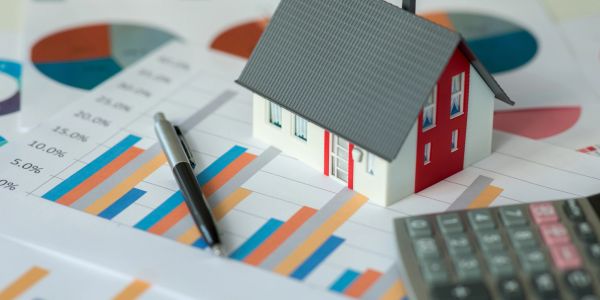 House model with financial charts and calculator