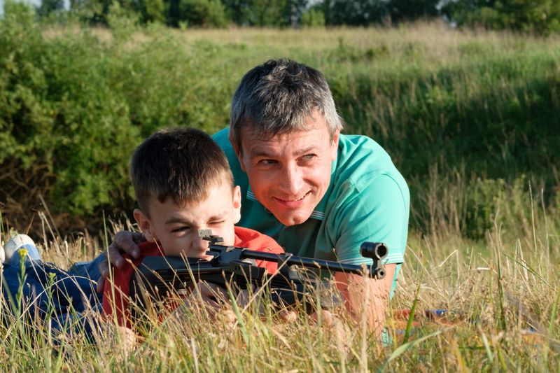Father teaches son to shoot air rifle