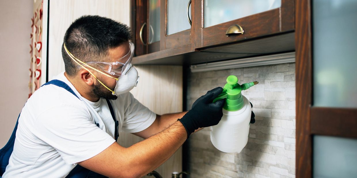 Man disinfecting kitchen with protective gear.