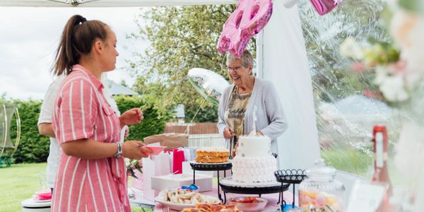 Two women celebrating with cake and decorations outdoors.