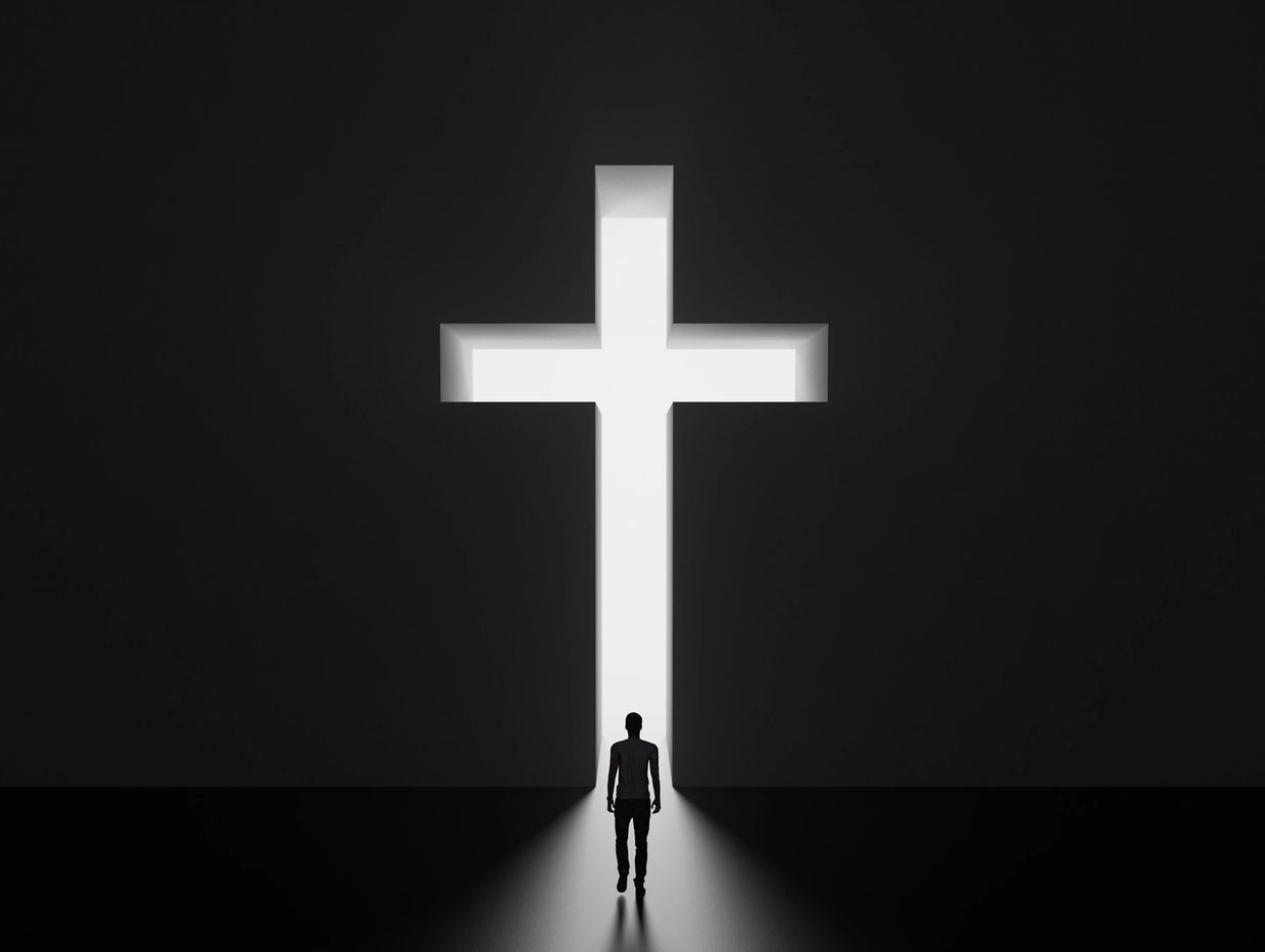Silhouette of a person walking towards a bright cross-shaped doorway.