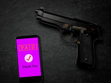 A handgun lies beside a smartphone displaying a paid confirmation screen.