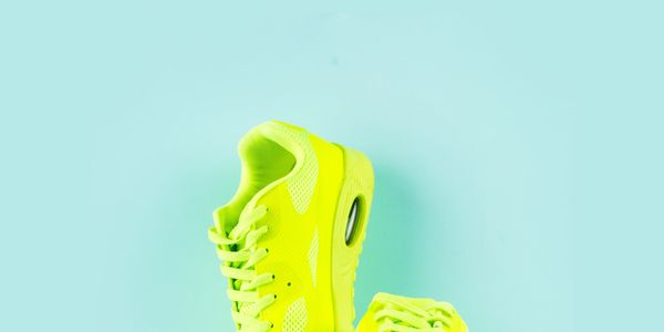 Bright neon yellow sneakers against a pale blue background.