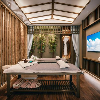 Serene spa room with two massage tables and bamboo decor.