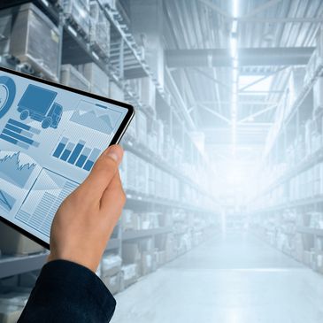 Person holding tablet showing logistics data in a warehouse aisle.