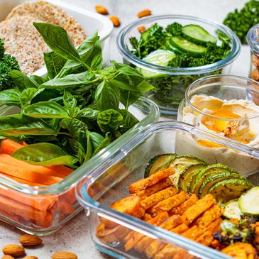 Fresh vegetables and healthy snacks arranged in glass containers.
