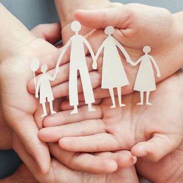 Hands holding paper cutout of a family of four, symbolizing unity and care.