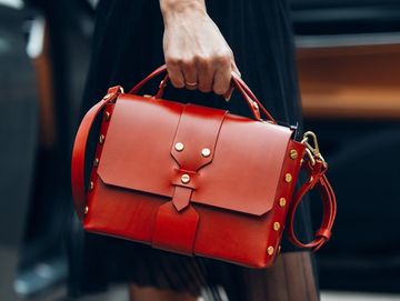 Woman holding a stylish red leather handbag.