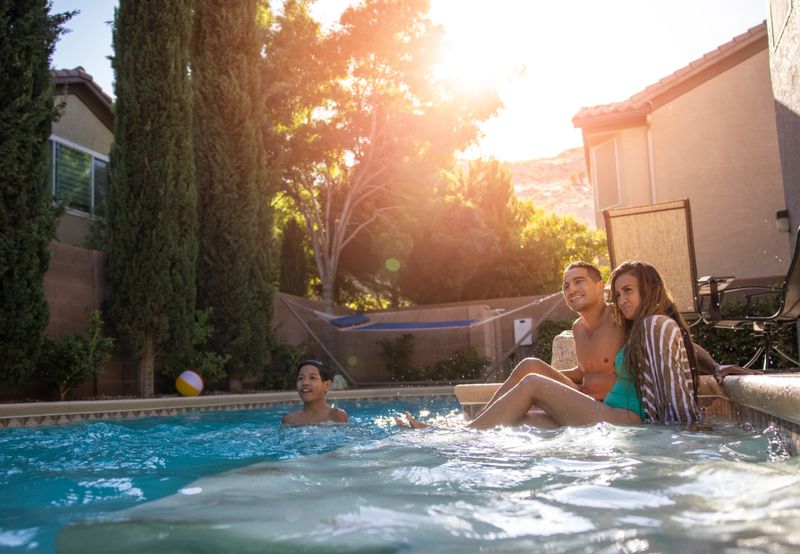 A family enjoying their backyard an pool on a hot summer day.