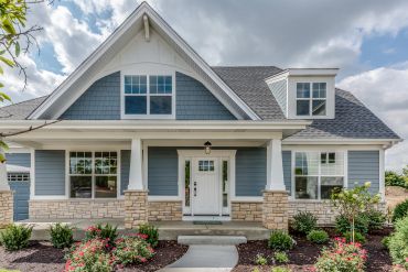 Blue house with white trim and a landscaped front yard.