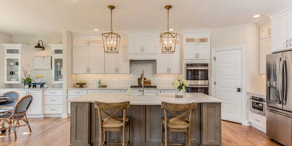 Bright modern kitchen with a large island and wooden chairs.