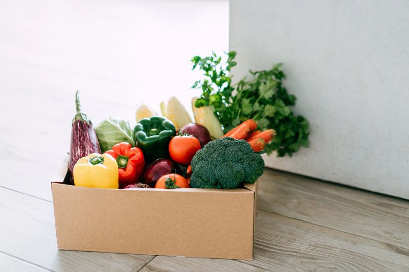 Home delivery of a box full of colourful and fresh organic groceries ordered online delivered at the door step