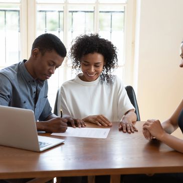 Photo shows a couple signing documents as a first time home buyer