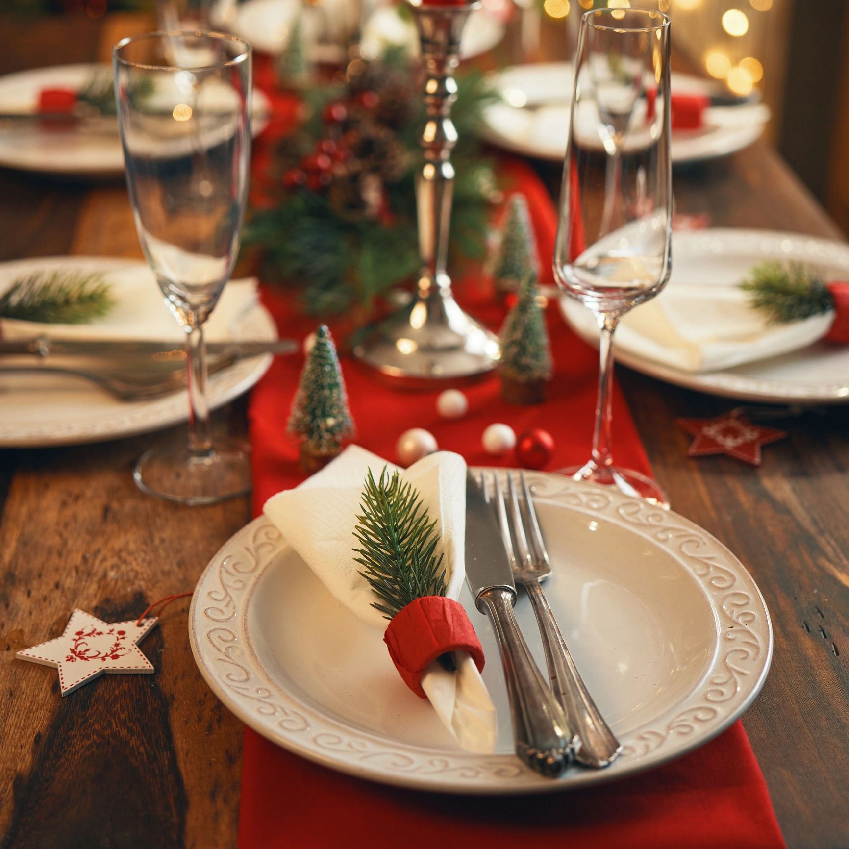 Festive holiday table setting with elegant plates, cutlery, and Christmas-themed decorations.