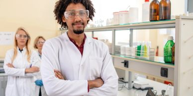 Confident scientist in lab coat with team in laboratory.