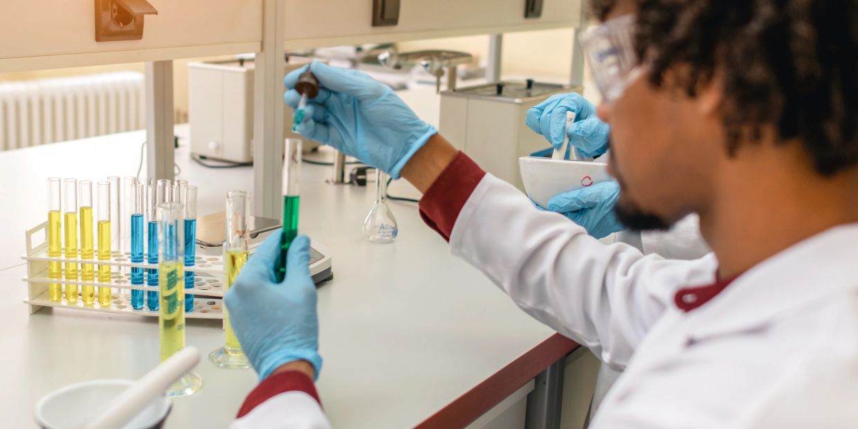 Scientist adding liquid to a test tube in a lab.