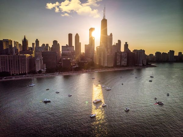 Sunset over a city skyline with boats on water.